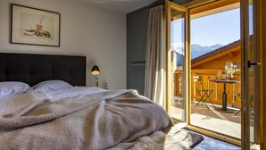 A bedroom with a large bed, a view of the balcony, and a framed picture on the wall. - Shed HOTEL (Bagnes)