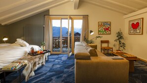 A hotel room with a bed, a sofa, a dining table, and a view of mountains through the windows. - Shed HOTEL (Bagnes)