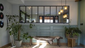 A room with a large mirror, a wooden bench, and potted plants. - Shed HOTEL (Bagnes)