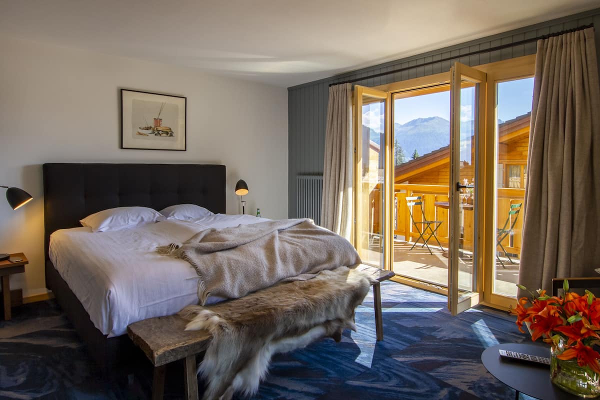 Ein Schlafzimmer mit einem großen Bett, einer Bank, einer Fernbedienung und einem Blumenstrauß.
