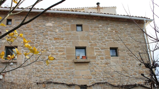 Un edificio de piedra con varias ventanas pequeñas y un techo plano.