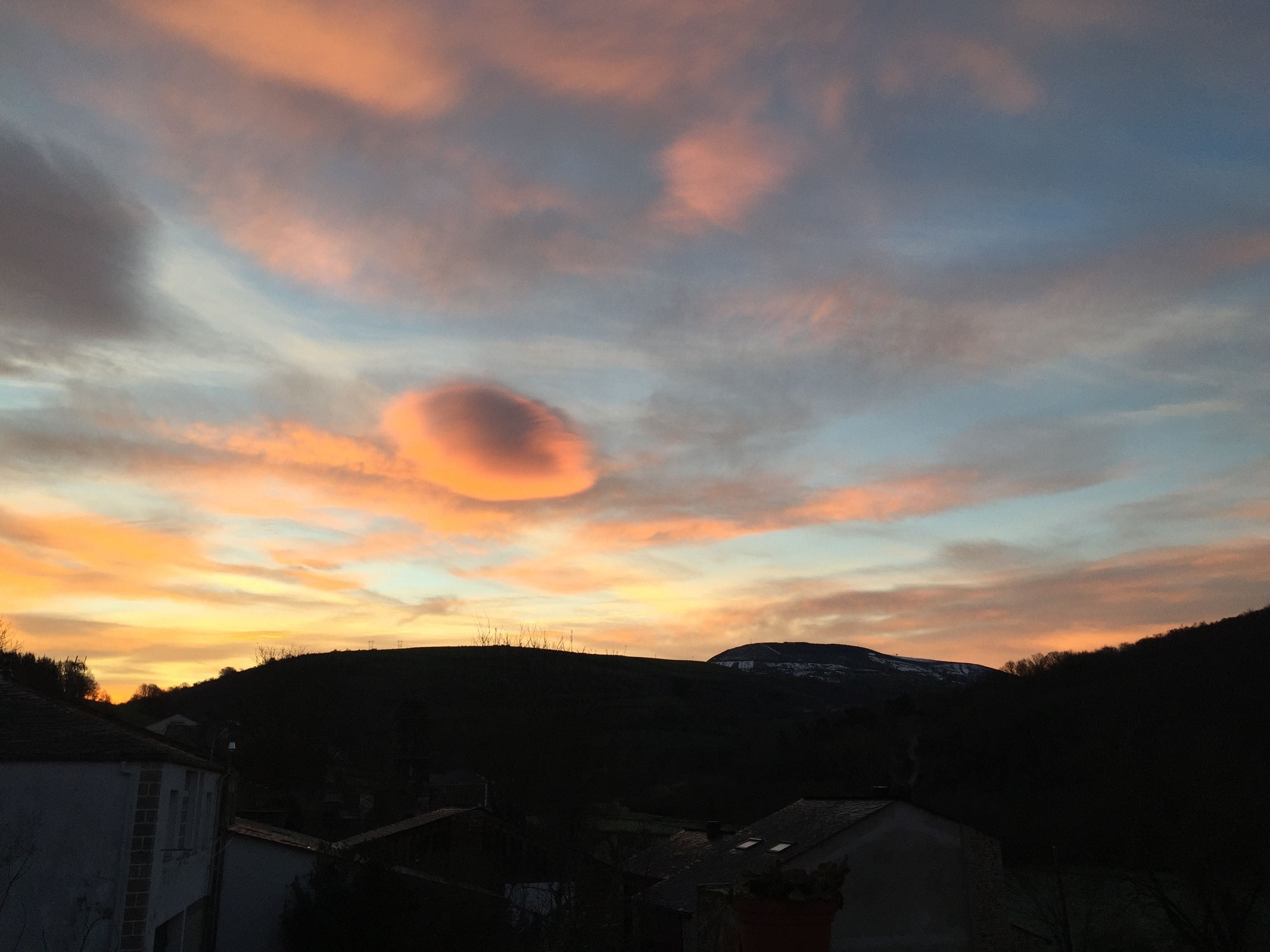 Tramonto su un paesaggio collinare con una strada che conduce a un edificio.
