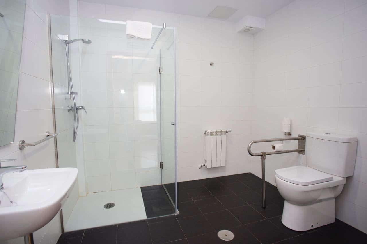 Un bany modern amb un'amplitud de vidre, un lavabo blanc i un vàter.