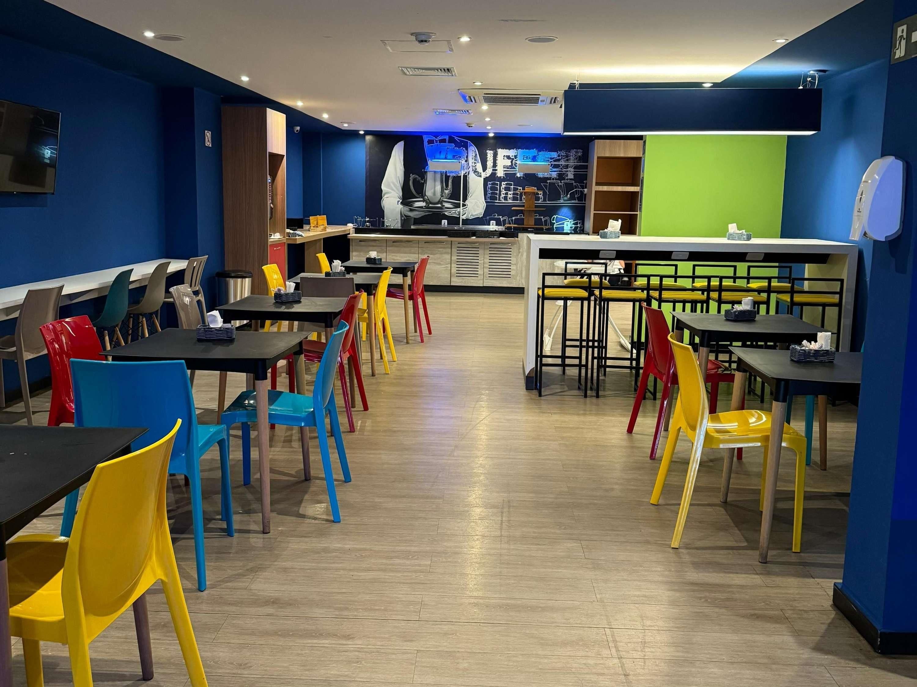 Un restaurant avec plusieurs tables et chaises, un comptoir et un mur aux couleurs bleu et vert.