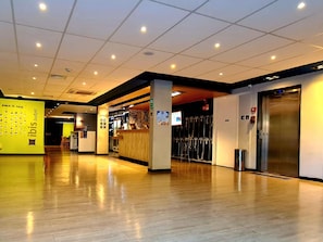 A hotel lobby with a reception desk, a wall-mounted display, and an elevator. - ibis budget Petropolis (Petrópolis)