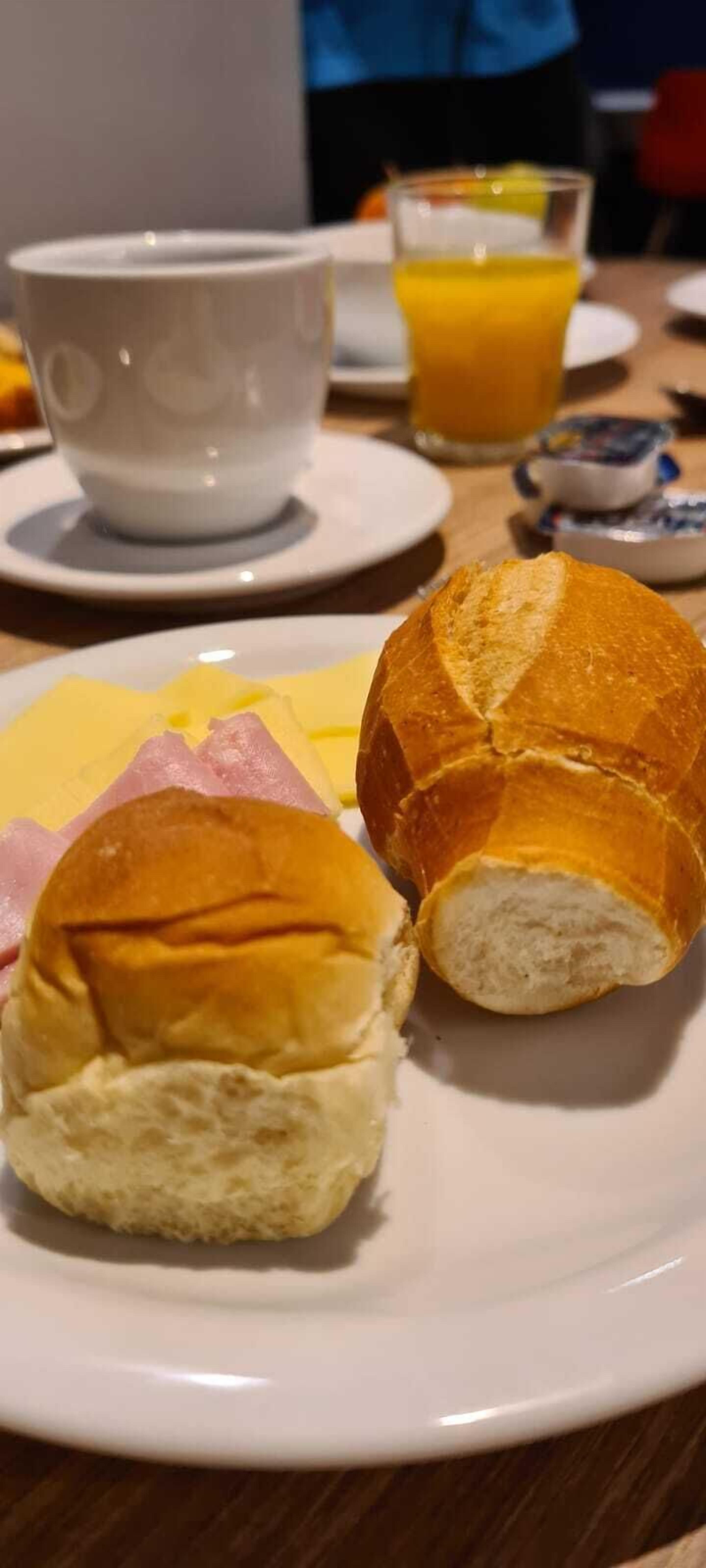 Un plato con dos sándwiches pequeños y una taza de café sobre una mesa.