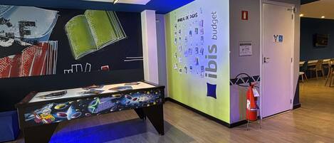 A room with a pool table, a wall with a mural, and a door with a fire extinguisher.