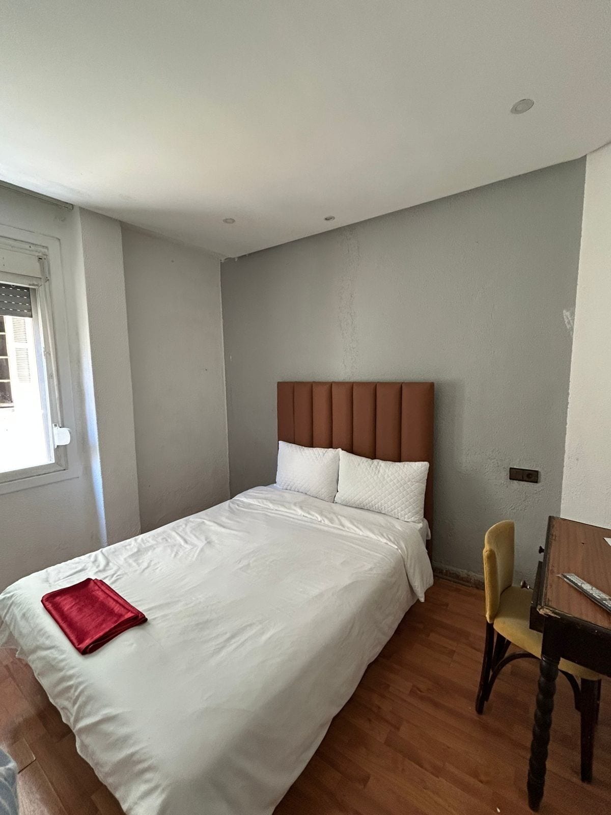 A bedroom with a bed, a chair, and a desk.