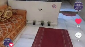 A hotel reception area with a sofa, a red carpet, and a desk. - Hotel Astoria (Tangier)