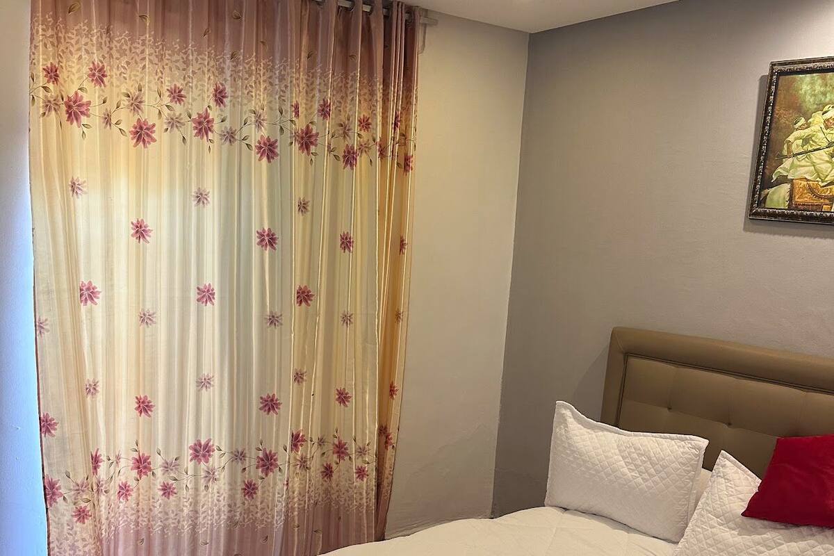 Una habitación de hotel con una cama grande, cabecera y un cuadro en la pared.
