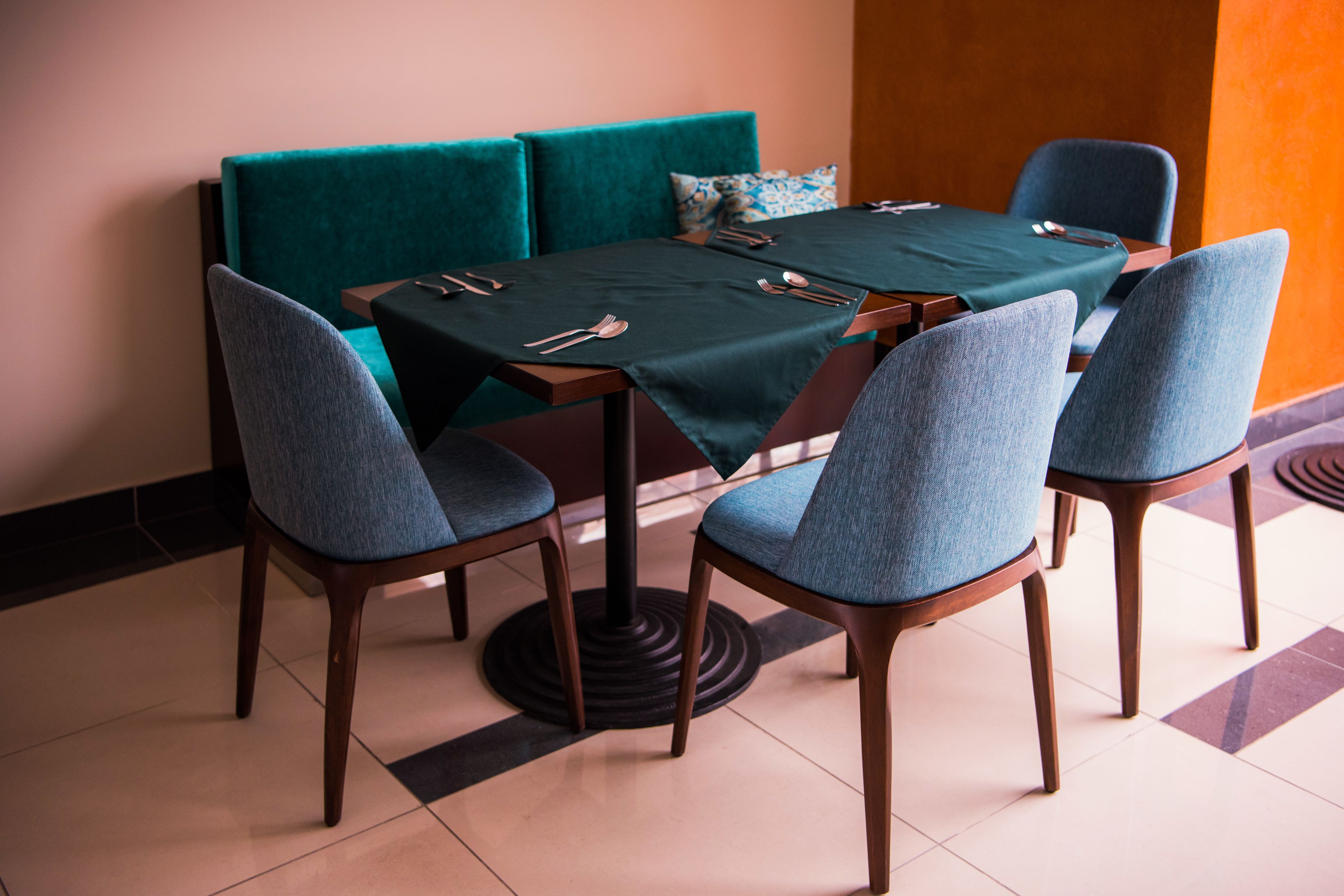 Comedor con una mesa dispuesta para cuatro personas, rodeada de cuatro sillas con tapicería azul.