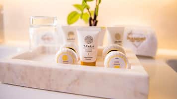 Una bandeja con champú, acondicionador y gel de baño de la experiencia de lujo ZAYAH, sobre una superficie de mármol.