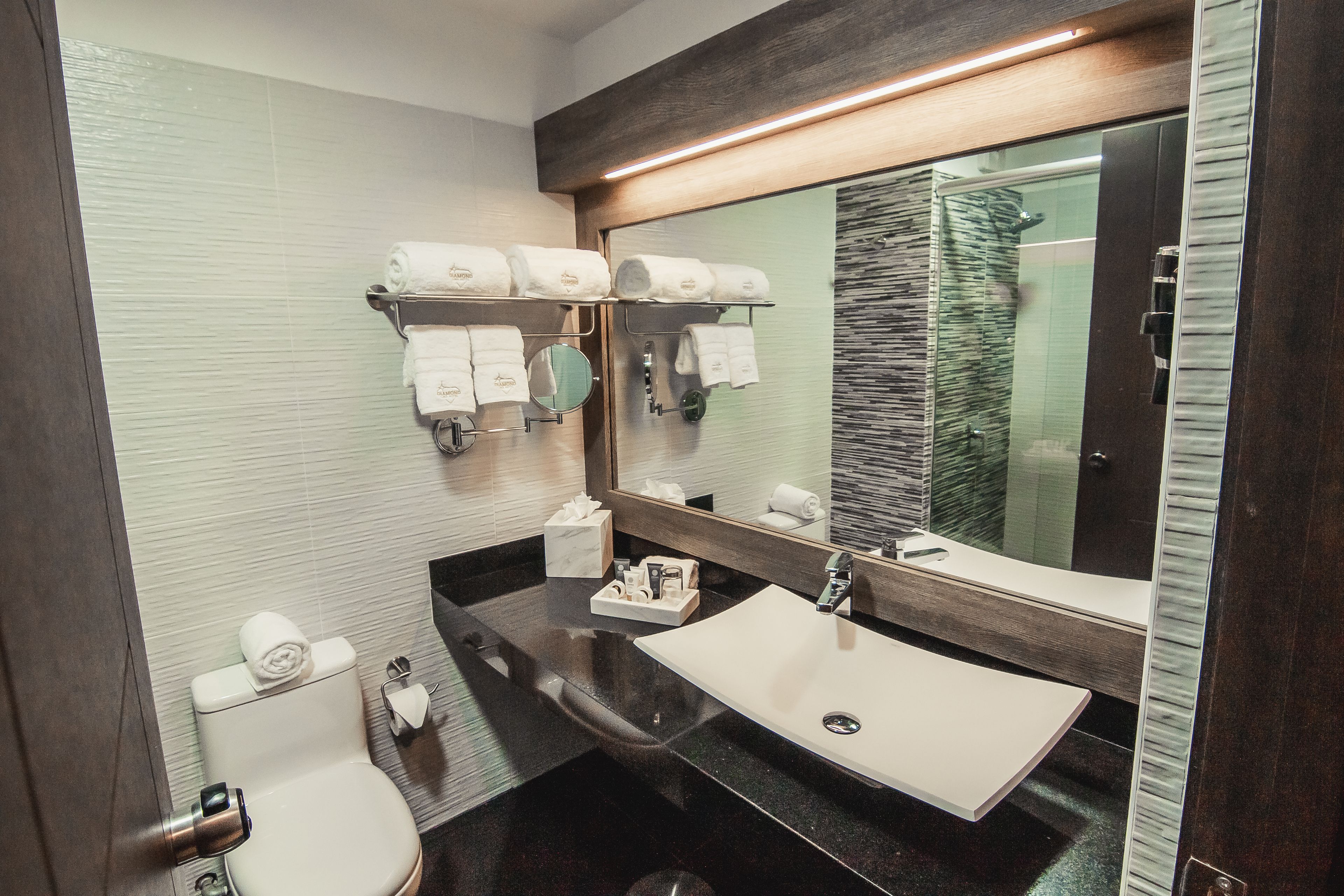 A modern bathroom with a white sink, a large mirror, and a towel rack with neatly folded towels.