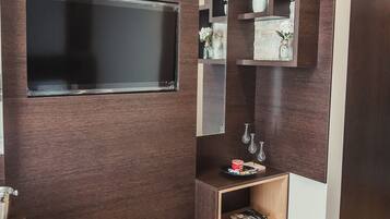 A modern living room with a dark wood accent wall, a flat-screen TV, and built-in shelving with decorative items.