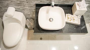 A bathroom with a toilet, sink, and toiletries.