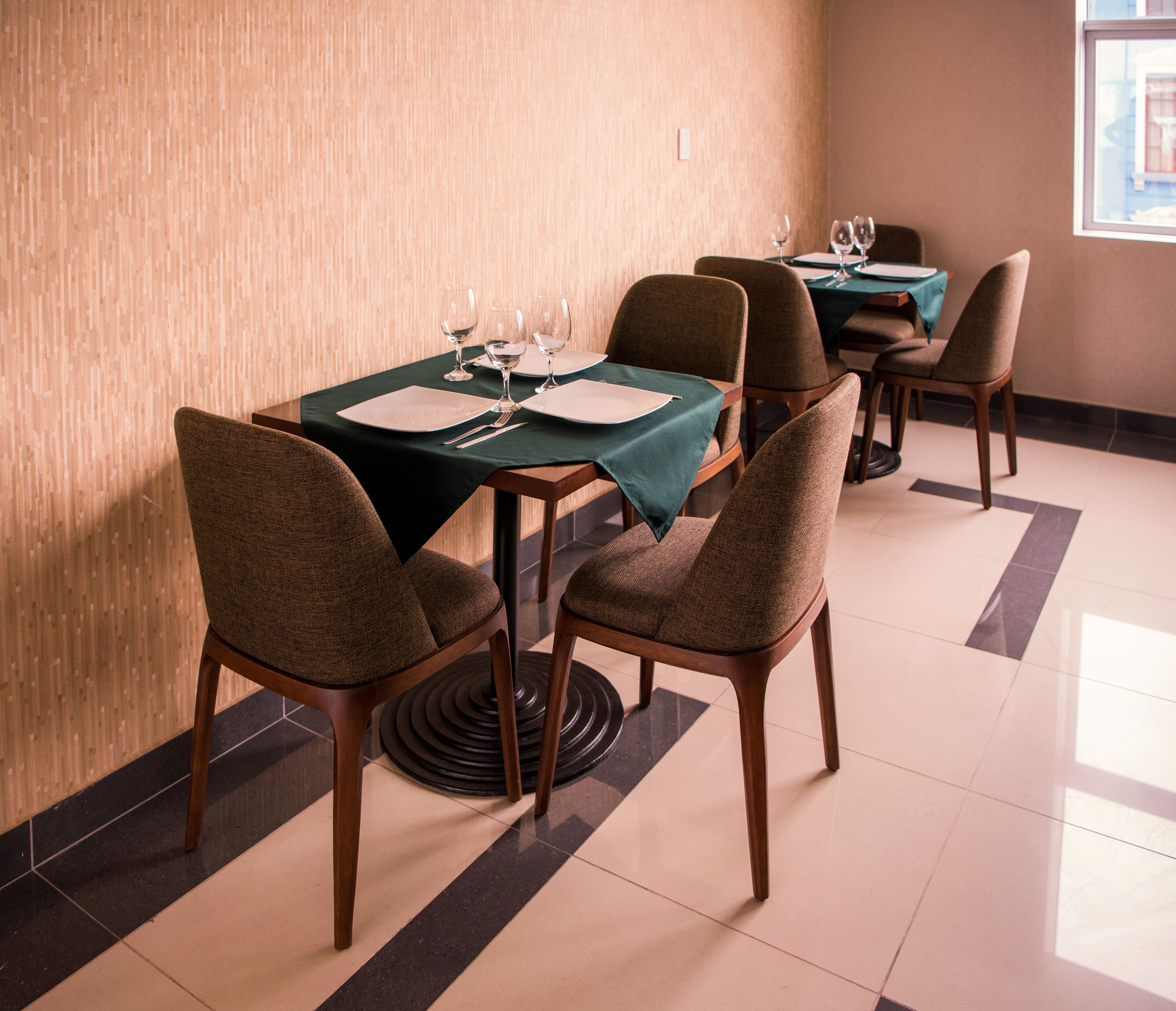 Comedor con una mesa dispuesta para cuatro personas, incluyendo platos, cubiertos y copas de vino.