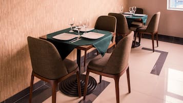 Comedor con una mesa dispuesta para cuatro personas, incluyendo platos, cubiertos y copas de vino.