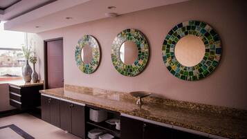 A modern kitchen with a granite countertop, dark cabinets, and three mosaic mirrors on the wall.