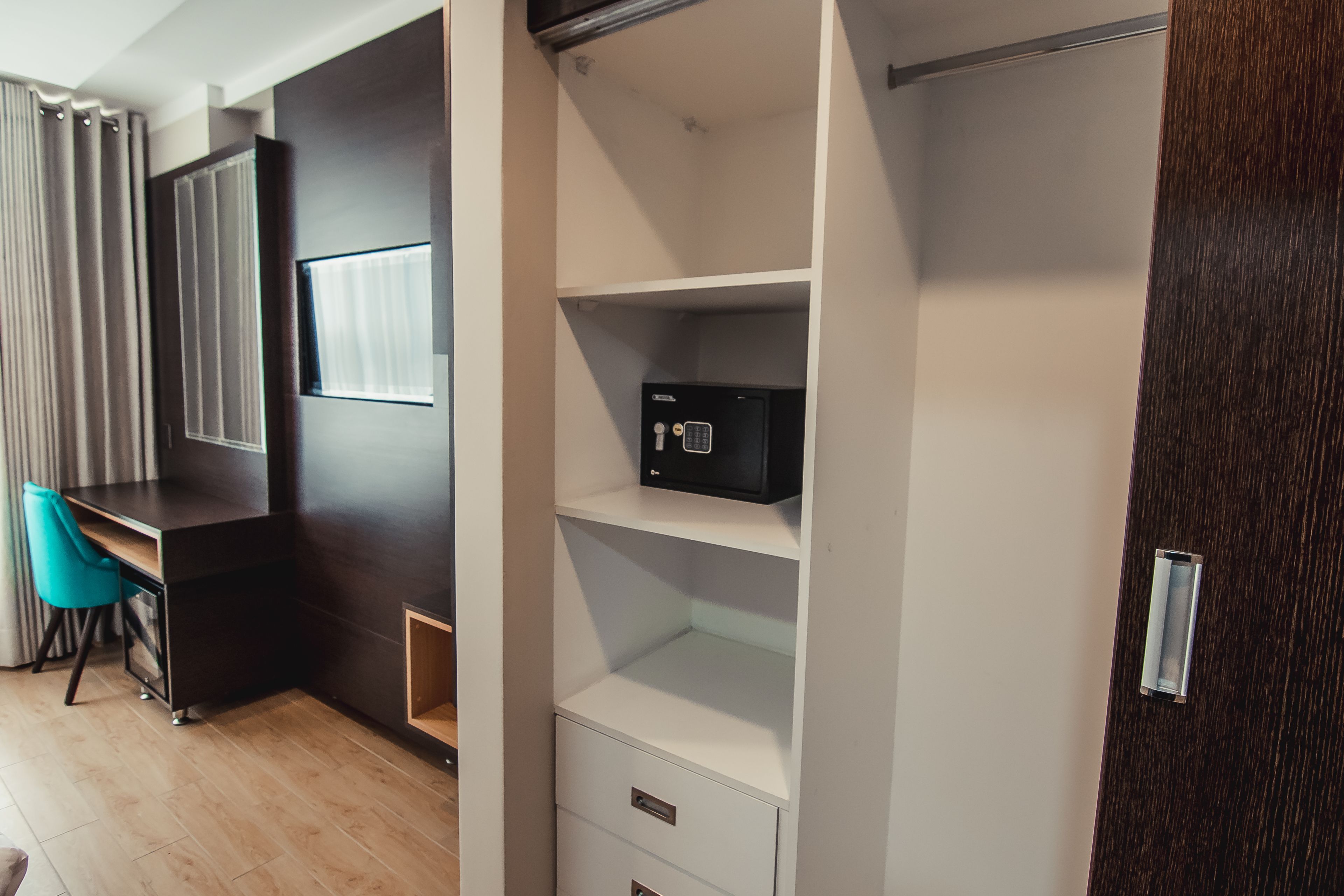A modern room with a wooden desk, a chair, a white shelving unit, and a dark wooden door.