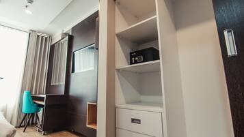 A hotel room with a bed, a desk, a chair, a wardrobe, and a window with curtains.