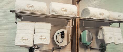 A bathroom with a towel rack holding several white towels with "Diamond Luma Hotel" branding.