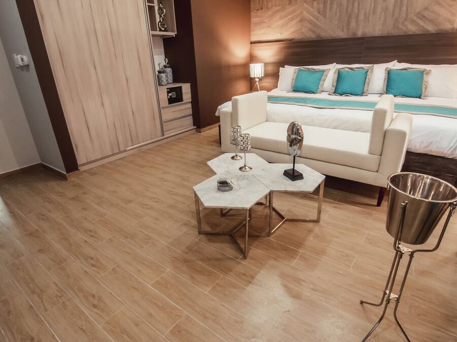 Una habitación de hotel con cama, sofá, mesa de centro y lámpara de pie.