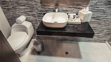 Un baño moderno con un lavabo de mármol, un inodoro y un bidé.
