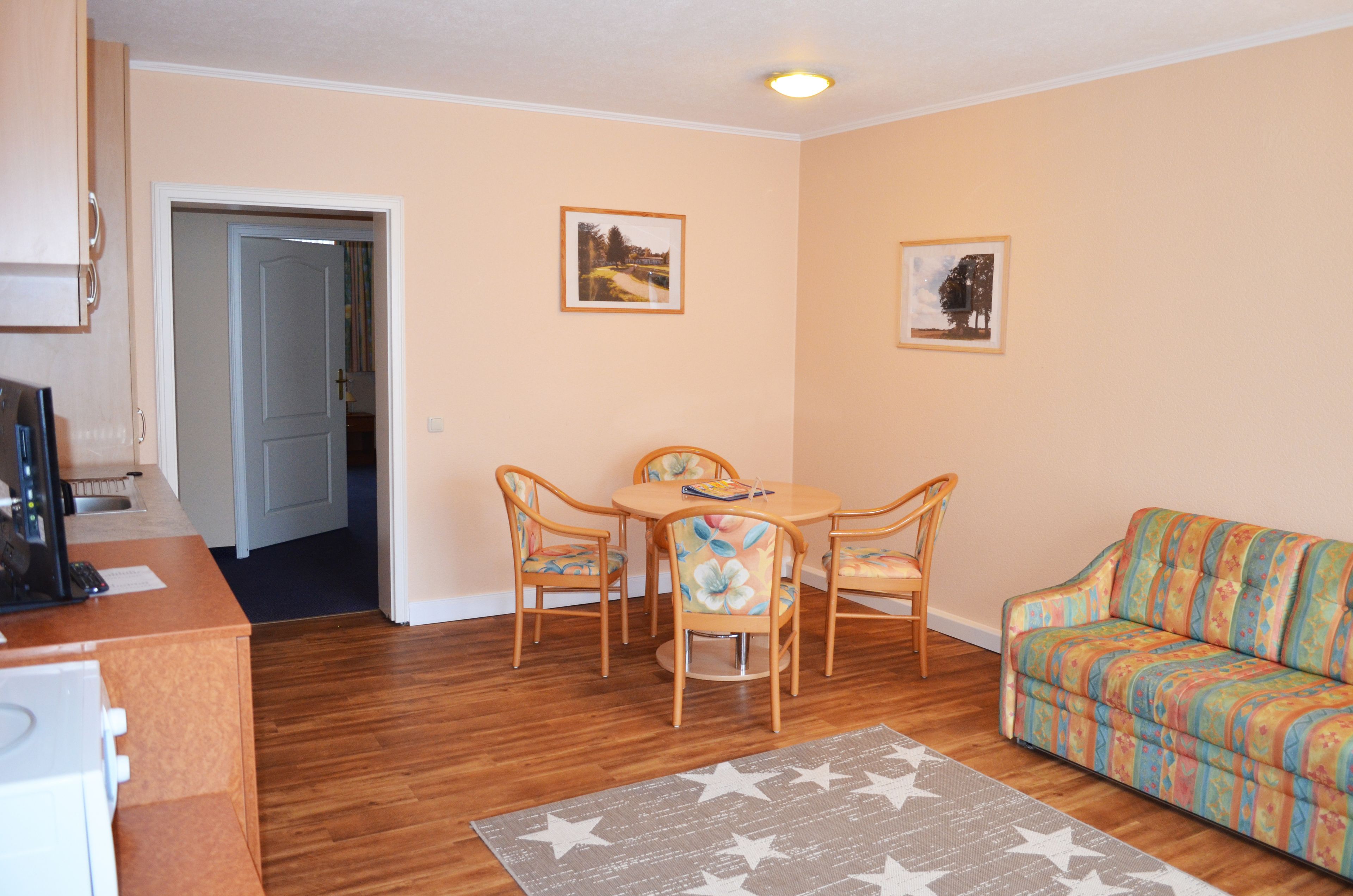 A compact living space with a dining area, a sofa, and a kitchen area.