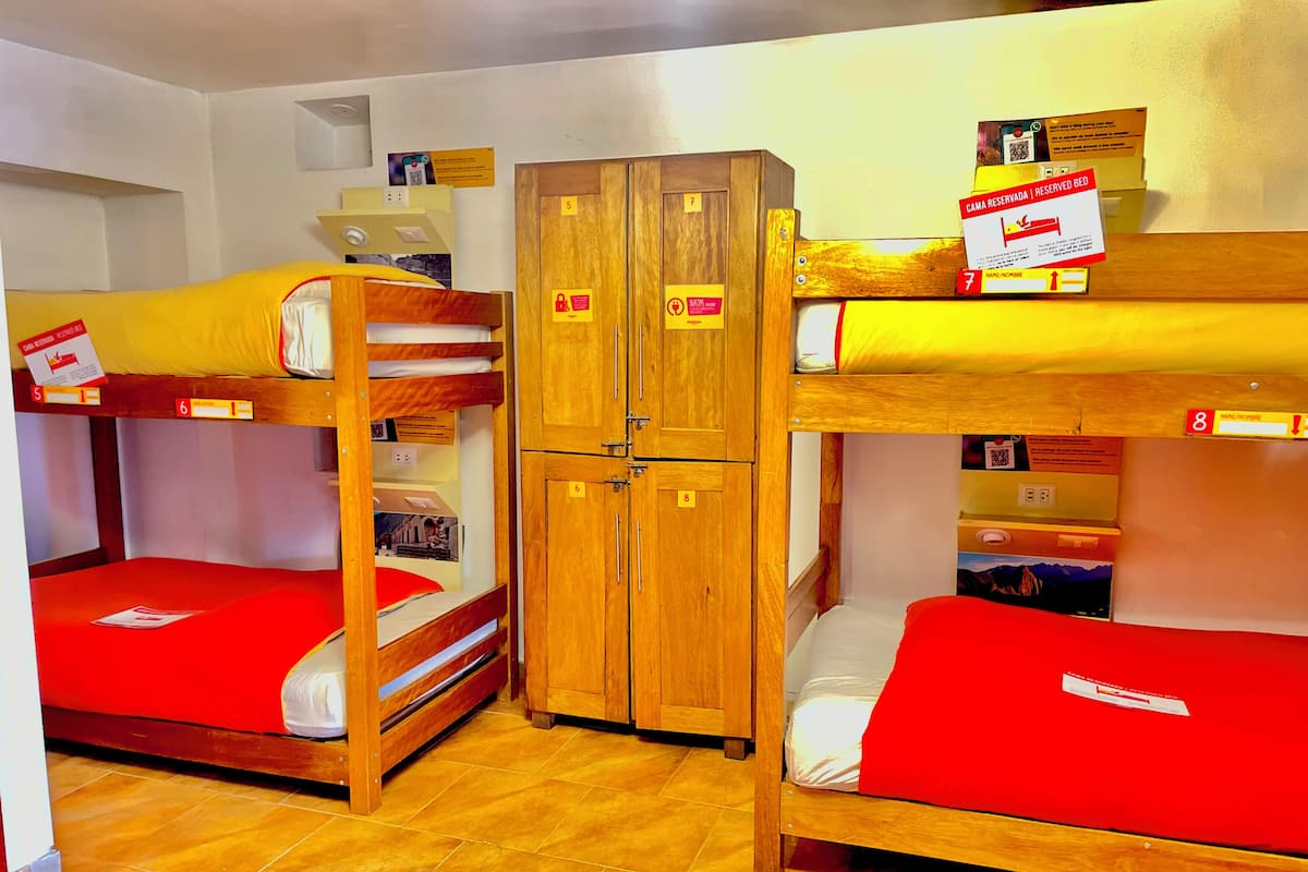 Un dormitorio con literas, armarios de madera y una colcha roja.