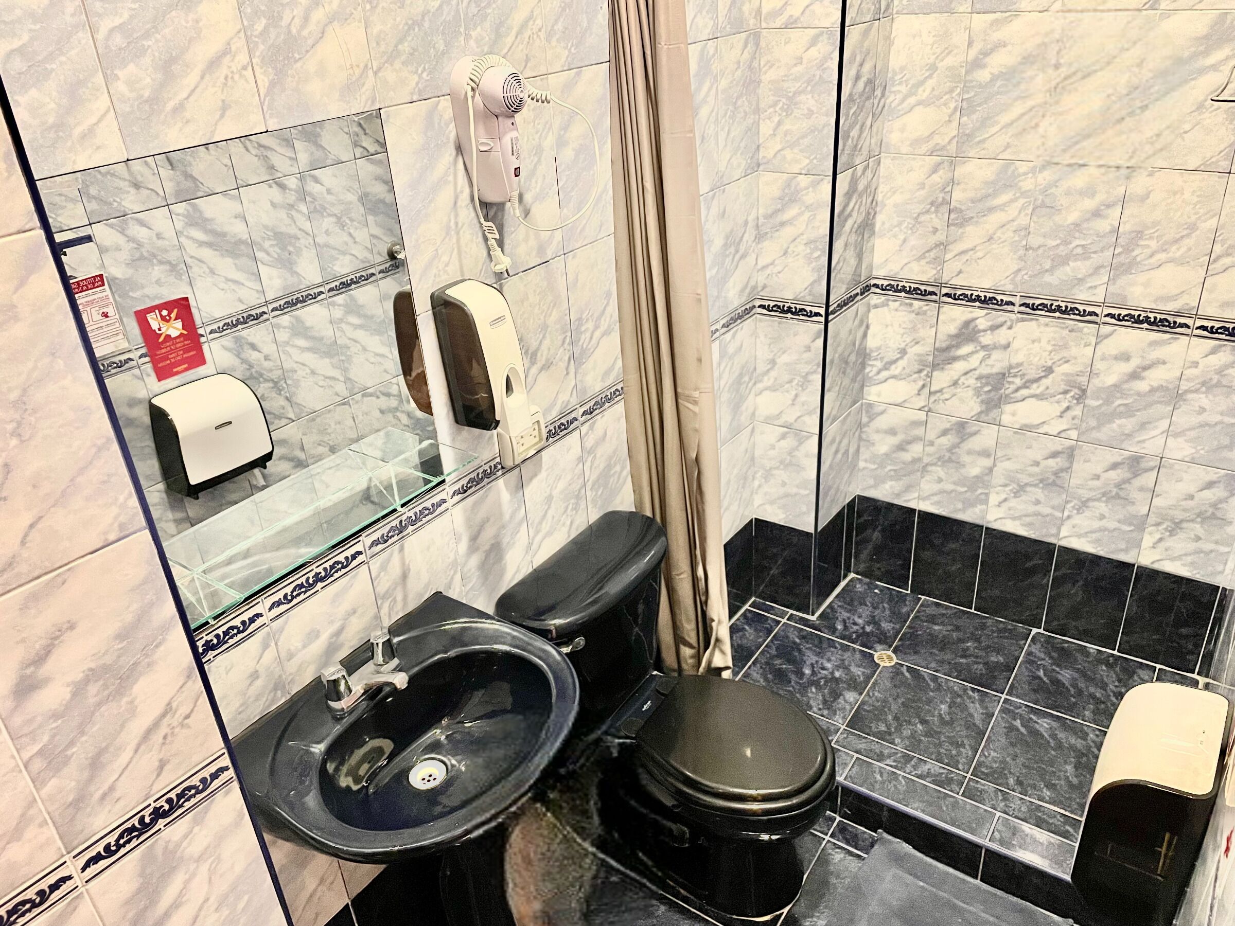 A bathroom with a black toilet, a sink, and a hand dryer.