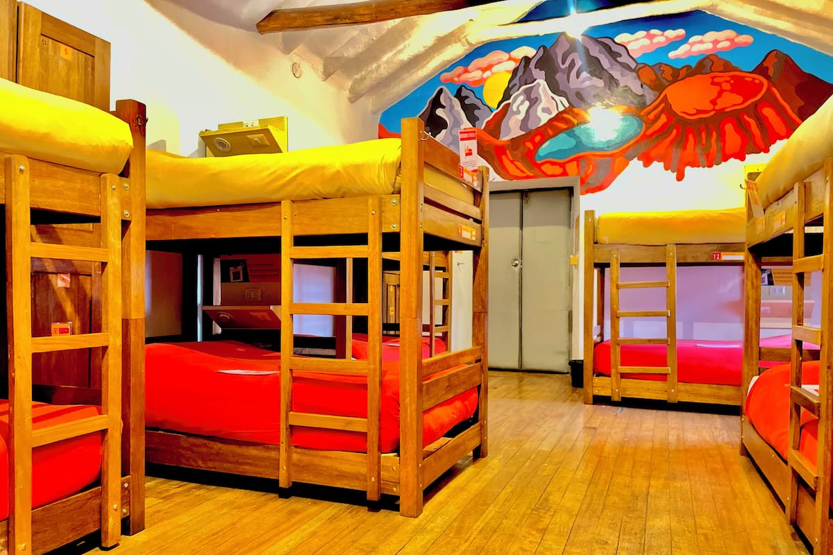 Habitación con literas, suelo de madera y un mural en la pared.