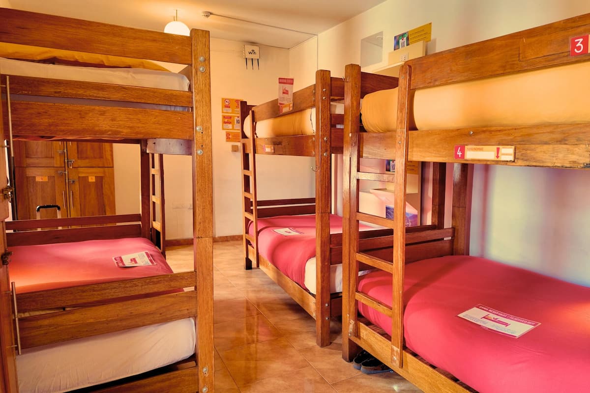 Un dormitorio con literas, barandillas de madera y suelo de baldosas.