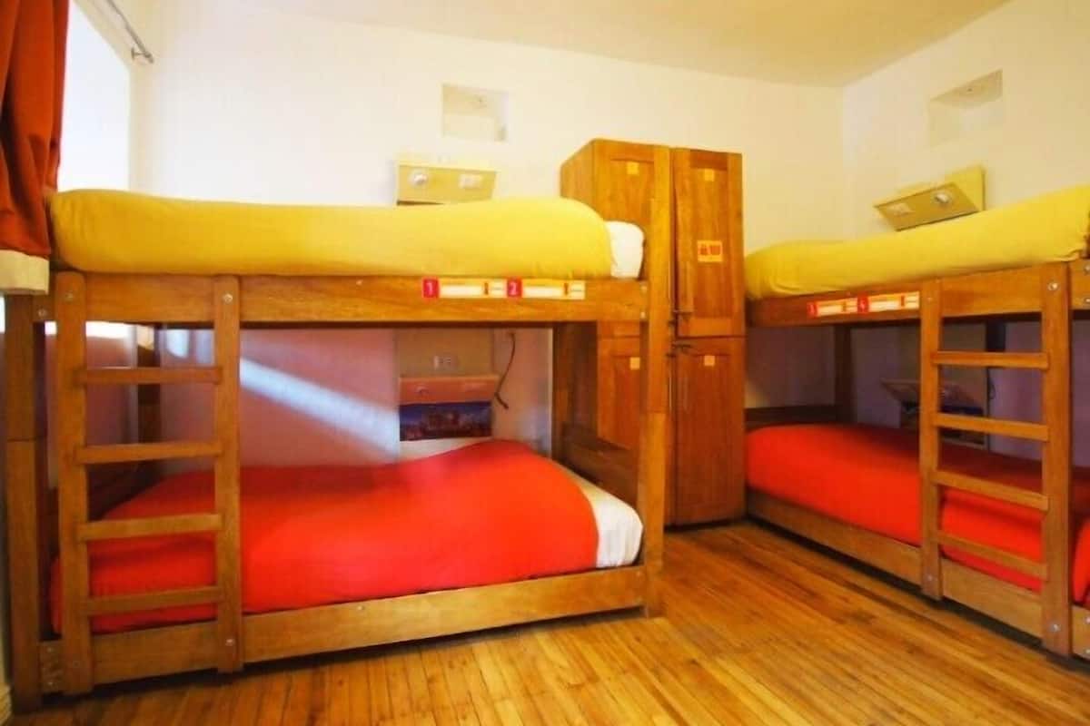 Una habitación con literas, armarios de madera y una ventana con cortinas.