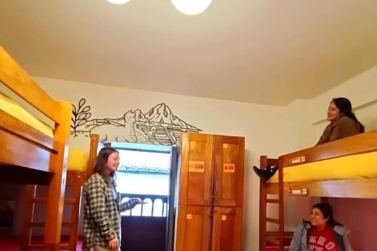 Una habitación con literas, una puerta de madera y un mural en la pared.