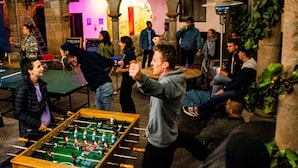 A group of people playing foosball in an indoor setting with stone arches and a foosball table. - Pariwana Hostel Cusco - Adults only (Cusco)