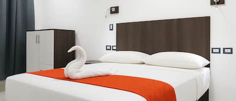 A hotel room with a bed, a wardrobe, and a swan-shaped towel.
