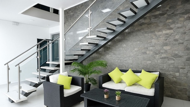 A modern interior with a staircase, black wicker furniture, and a stone wall. - Hotel Milan Costa Rica (San José)