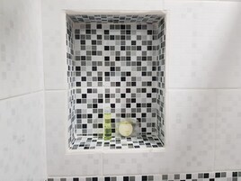 Casa de banho com parede revestida a mosaicos, apresentando um padrão xadrez em preto e branco.