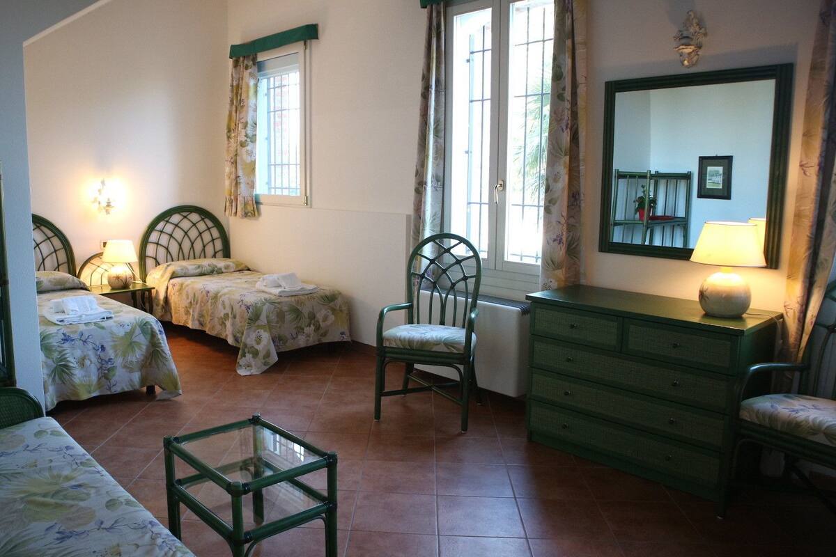 Ein Schlafzimmer mit zwei Betten, einem Sessel, einem Schminktisch und einem Spiegel.