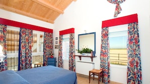 A bedroom with a bed, a chair, a mirror, and a window with curtains. - Agriturismo Sesta Presa (Caorle)