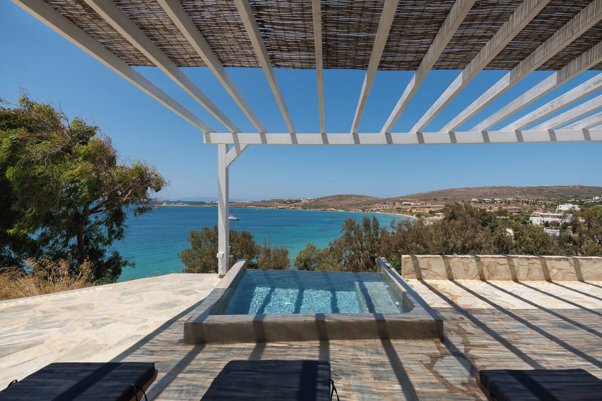 A rooftop infinity pool with a view of the sea and a distant town.