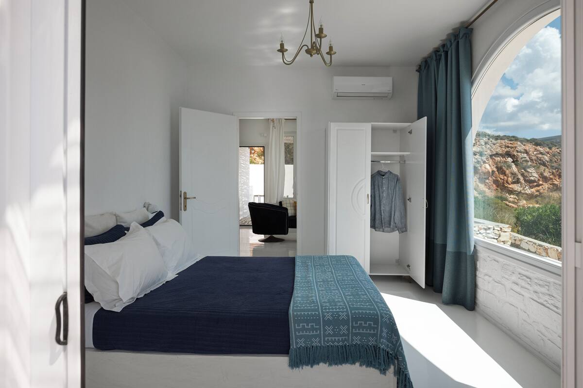 A bedroom with a bed, a view of the outdoors, a chandelier, and a wardrobe.