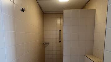 Ein kleines Badezimmer mit Fliesen, einer Toilette, einer Duschkabine und einem Handtuchhalter.