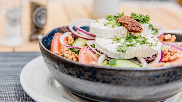Un tazón de ensalada con queso, nueces y verduras.