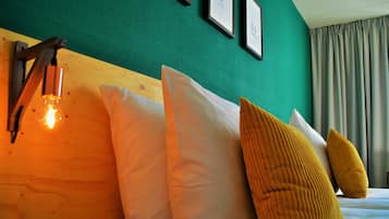 A bed with white and yellow pillows, a wooden headboard, and a wall-mounted light fixture.