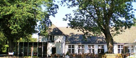 A building with a tiled roof, large windows, and a courtyard with outdoor seating.