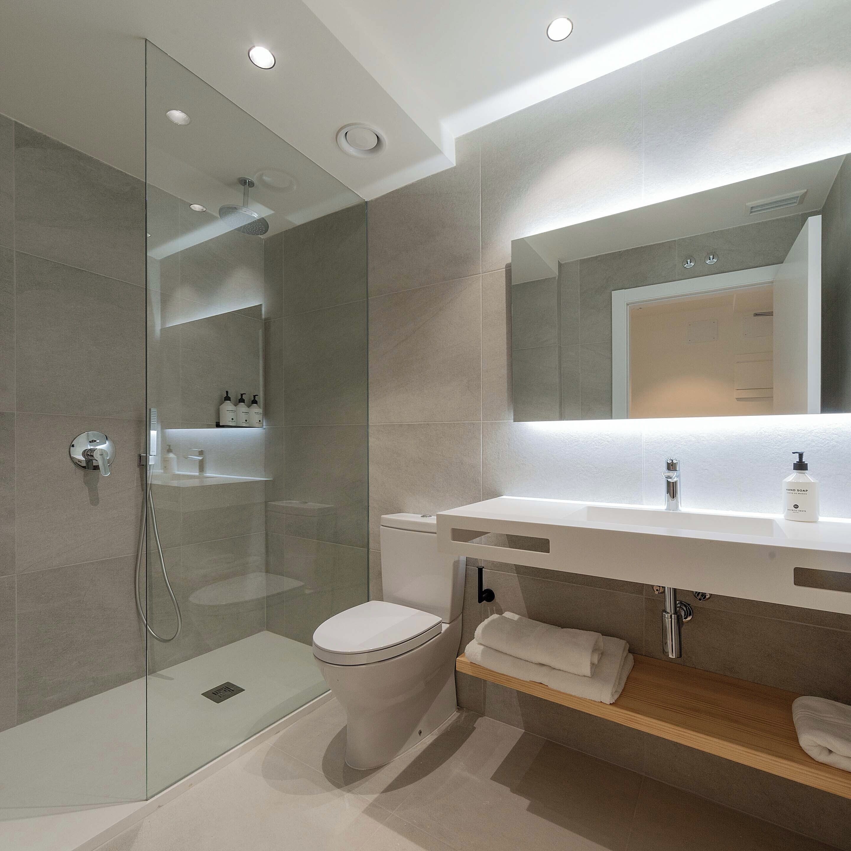 A modern bathroom with a glass-enclosed shower, a white toilet, a vanity with a mirror, and a towel rack.