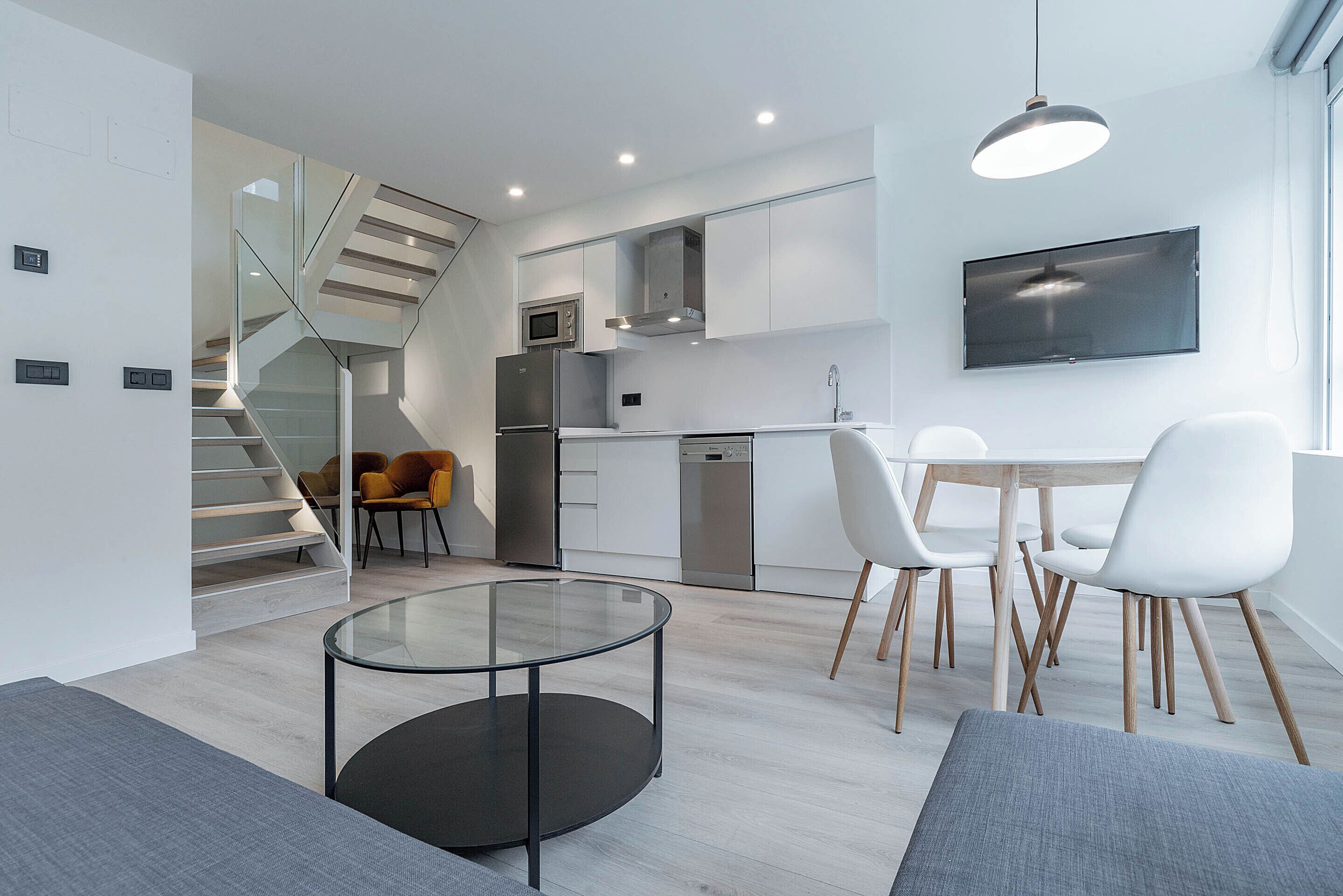 A modern kitchen with white cabinets, a built-in microwave, and a stainless steel refrigerator.