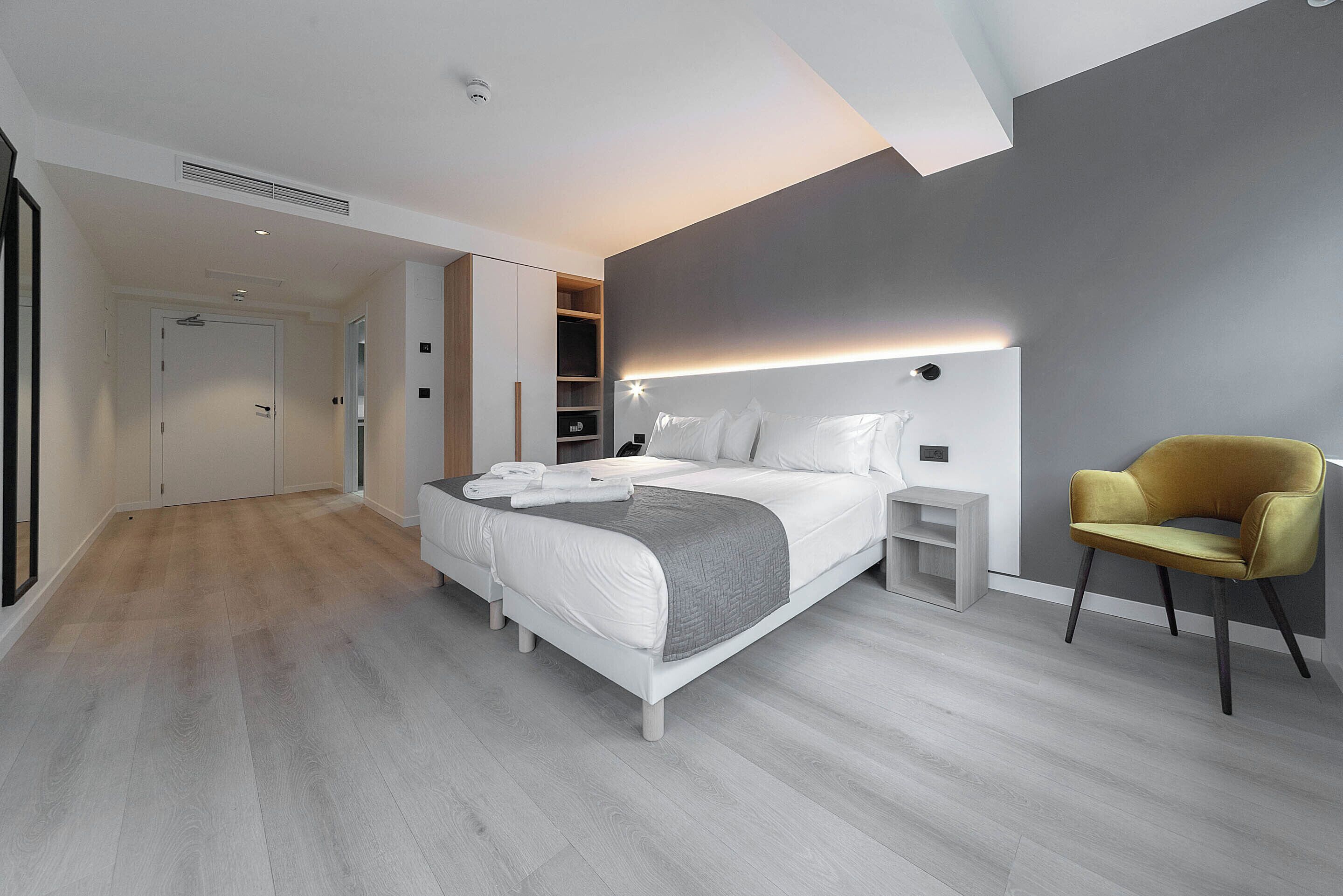 A modern bedroom with a bed, bedside tables, a chair, and a built-in wardrobe.