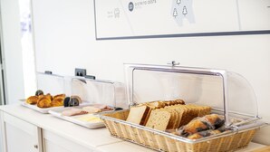 Un mostrador de buffet amb pa i pastissos en recipients transparents.